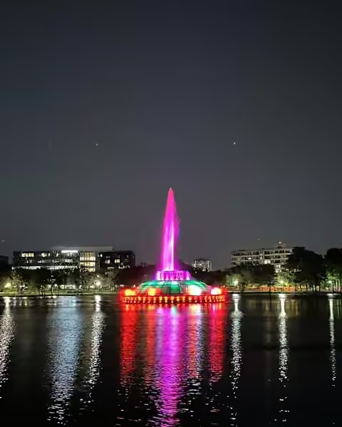 The Lake Eola fountain glowing pink, green and red at night